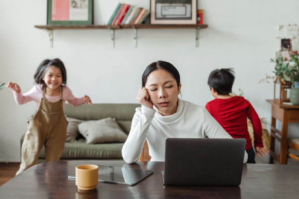 weary mom with toddlers running in the background