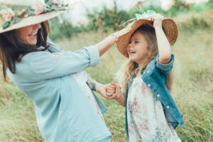 Mom and little girl with hats in a field laughing